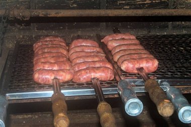 Şişe dizilmiş zanaatkar sosisler geleneksel barbekülerin tüm lezzetlerini ortaya çıkarmaya hazırdır. Doku, ışıltı ve gelenek doğal ışıkla yakalanır.
