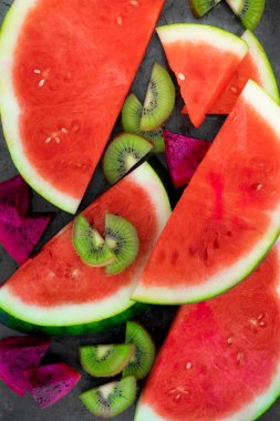 Klasik bir arka planda taze karpuz, kivi ve ejderha meyvesi dilimleri.
