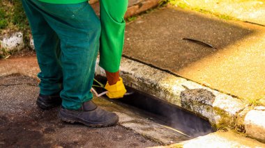 An exterminator applying pest control product to urban sewage systems, focusing on eradicating pests such as rodents and insects, ensuring hygiene and public health in the city environment clipart