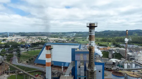 Sanayi süreçlerini ve kağıt imalatı sektöründeki fabrika emisyonlarının çevresel etkilerini vurgulayan, kağıt hamuru ve kağıt endüstrisine duman salan bacanın hava görüntüsü