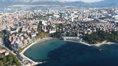 Hırvatistan 'ın Split kentindeki Bacvice Plajı' nın havadan görünüşü, kumlu kıyılarını, turkuaz suyunu ve güneşli Akdeniz iklimini sergileyerek plaj aşıkları ve turistler için popüler bir yer haline getiriyor..