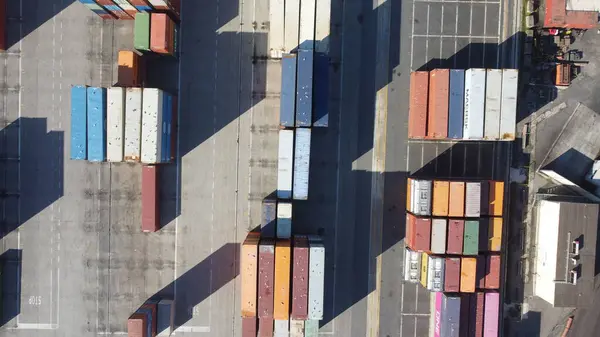 Bir konteynır limanının havadan çekilmiş fotoğrafı, istiflenmiş konteynırlar sergileniyor. Görüntü, küresel ticaret ve nakliye sektöründe yer alan yoğun sanayi merkezini vurguluyor