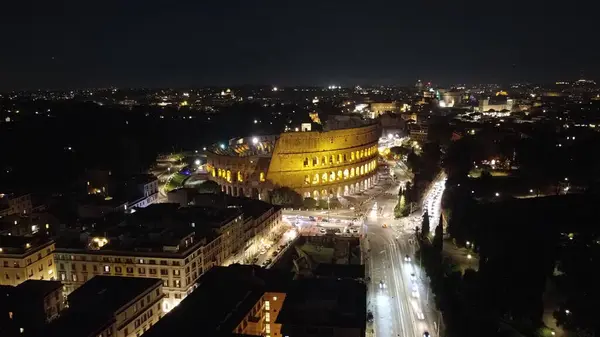 İtalya, Roma 'daki Colosseum' un gece aydınlatılmış bir fotoğrafı. Bu resim, bu tarihi anıtın ihtişamını yansıtıyor. Gece gökyüzünün altındaki antik amfitiyatronun çarpıcı manzarasını sunuyor.