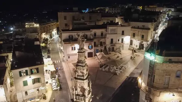 Geceleri İtalya 'nın Ostuni kentinin havadan görünüşü. Fotoğraf aydınlanmış beyaz şehri yakalıyor, gece gökyüzünün altında tarihi binalarını ve büyüleyici atmosferini sergiliyor, eşsiz güzelliğini vurguluyor.