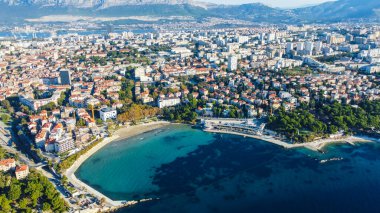 Hırvatistan 'ın Split kentindeki Bacvice Plajı' nda kristal berrak turkuaz su ve rahatlatıcı bir atmosferle güneşli bir gün. Fotoğraf, Dalmaçya kıyılarındaki bu popüler kıyı bölgesinin güzelliğini yansıtıyor.