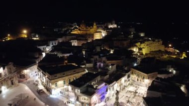 İtalya, Ostuni 'nin gece 4K insansız hava aracı görüntüleri. Video, tarihi mimarisi, dolambaçlı sokakları ve Akdeniz cazibesiyle aydınlanmış 