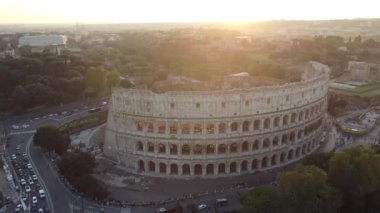 Roma, İtalya 'daki Kolezyum' un günbatımı videosu, antik amfi tiyatroyu aydınlatan sıcak altın ışığı yakalıyor, canlı gökyüzü ve çevresindeki tarihi şehir ile çarpıcı bir kontrast oluşturuyor.