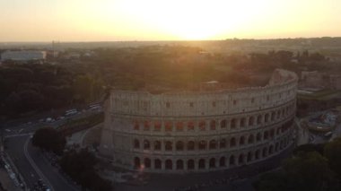 İtalya, Roma 'daki Kolezyum' un havadan görünüşü, açık mavi gökyüzü altında hareketli şehir manzarası ile çevrili ikonik mimarisini gözler önüne seriyor.