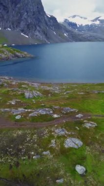 Huzurlu ve sakin bir göl görkemli dağlarla çevrenin çevresine kurulmuş canlı, yemyeşil bir göl.