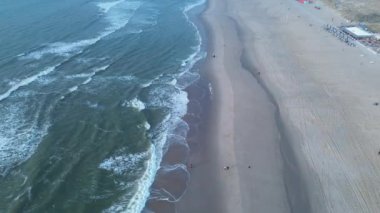 Bu çarpıcı hava fotoğrafında kumlu kıyıya vuran yumuşak dalgalarla sakin bir plaj sergileniyor.