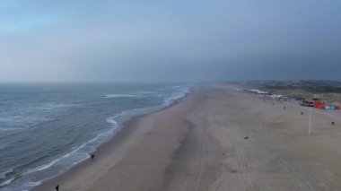 Huzurlu ve huzurlu bir sahil manzarası. Nazik, dalgaları sakin ve uzak bir ufuk manzarasının yanında yalpalayan.