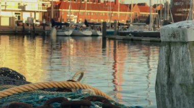 Güzel bir günbatımı saatinde sakin sulara yansıyan teknelerle sakin bir liman sahnesi.