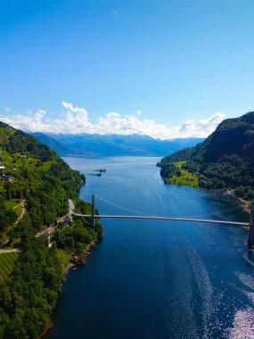 Hava görüntüsü, çarpıcı dağların arasından akan kıvrımlı bir nehrin manzarayı güzelleştiren bir köprü gösterdiğini gösteriyor.