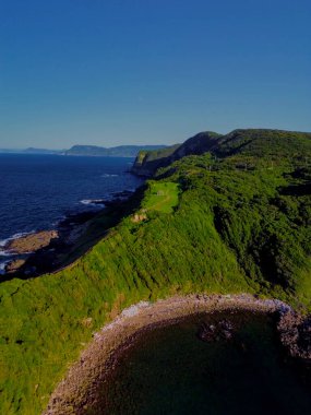 Nefes kesen kıyı manzarası canlı yeşil uçurumları sergiliyor sakin bir okyanus zeminine karşı muhteşem bir şekilde kurulmuş