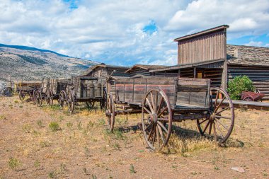 Vahşi Batı, Wyoming 'den antik at arabaları ve tarihi binalar. Antik at arabaları ve yüksek çöl arazilerindeki tarihi binalar dağlar, mavi gökyüzü ve ABD 'nin Wyoming kentinde bulutlar.. 