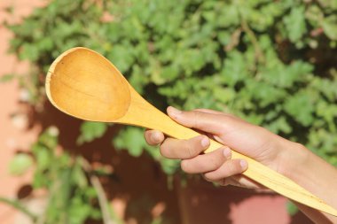 Tahta kaşık tutan bir el.