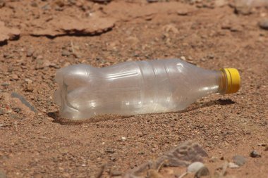 Yerde duran plastik bir şişenin yakın çekimi.