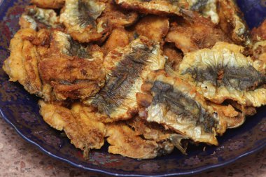 Elleri bir tabak kızarmış sardalya tutarken