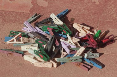 Colorful plastic clothespins on a reddish-brown surface