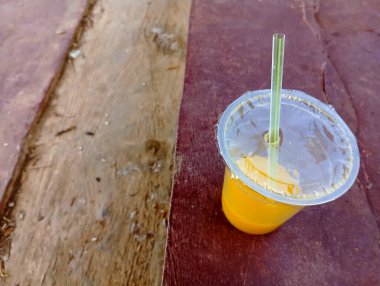 Masanın üzerinde plastik camlı portakal suyu.