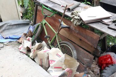 Pekanbaru, 31 Ekim 2024, yeşil bir BMX bisikleti çeşitli itemlerle çevrili ahşap bir masaya yaslanıyor..