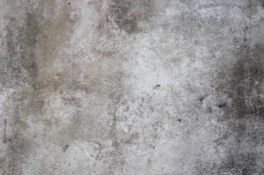 Fotoğraf beton bir duvarın yakın çekimini gösteriyor. Duvarın pürüzlü, desenli bir yüzeyi vardır ve açık gri renktedir..