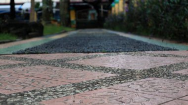 Geçit kırmızı fayanslarla döşenmiştir. Karmaşık çiçek desenleriyle süslenmiştir. Küçük, karanlık çakıl taşlarıyla çevrelenmiştir..