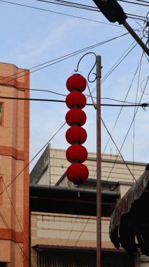 A string of red lanterns is hanging from a lamp post. clipart