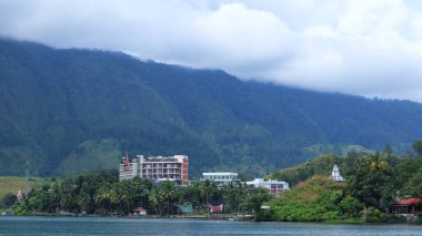 Danau Toba, 09 Kasım 2024, Endonezya 'nın başkenti Sumatra Utara' da yemyeşil dağlarla çevrili sakin bir gölün kıyısında modern bir otel kurulmuştur..