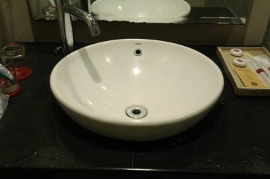 Pekanbaru, 21 Kasım 2024, Görüntü minimalist bir banyo kibrini gösteriyor, yuvarlak, beyaz bir porselen lavabo..