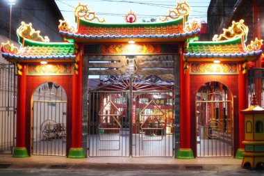 Bagansipaiapi,02 December 2024,-A front view of a traditional Chinese temple gate, adorned with intricate carvings and bright red paint. The gate is illuminated by warm, golden lights.Rokan Hilir. clipart