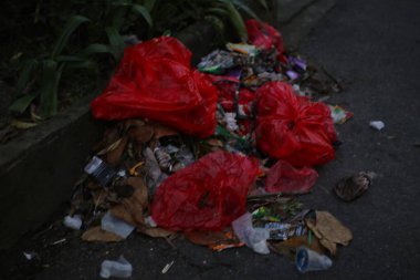 Kirli bir sokakta kırmızı çöp torbaları..