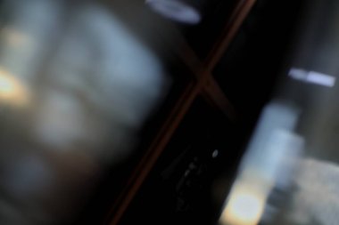 Pencere camının koyu, çarpık bir yansıması parlak bir yüzeyde görülebilir..