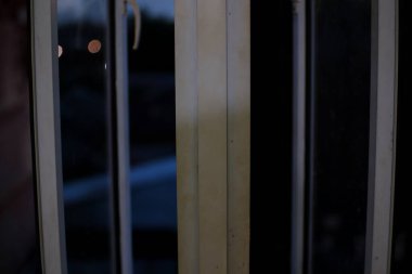 Leke ve çiziklerle dolu kirli, eski bir pencere çerçevesinin yakın çekimi. Cam biraz sisli, dışarıyı göremiyoruz..