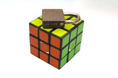 A colorful Rubik's Cube is topped with a rusty padlock. clipart