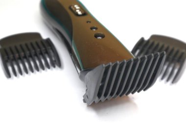 Birden fazla ayarlanabilir tarağı olan kablosuz bir saç makası temiz, beyaz bir arkaplan karşısında gösterilir.