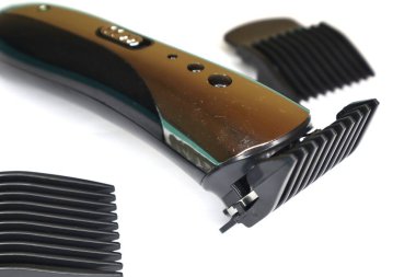 Birden fazla ayarlanabilir tarağı olan kablosuz bir saç makası temiz, beyaz bir arkaplan karşısında gösterilir.