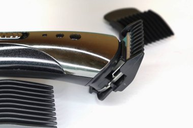 Birden fazla ayarlanabilir tarağı olan kablosuz bir saç makası temiz, beyaz bir arkaplan karşısında gösterilir.