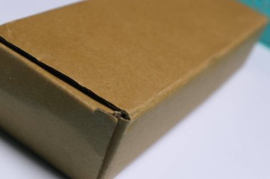 Kahverengi bir karton kutu beyaz bir yüzeye yerleştirilir..