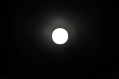 Parlak beyaz bir çember, koyu bir zıtlık yaratan bir zemin etrafında toplanır. Görüntü yumuşak, hafif bulanık bir kaliteye sahip, ona soyut ve minimalist bir his veriyor. Bu, gök cisimlerini ya da spot ışığı efektini temsil etmek için kullanılabilir.