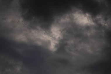 Fırtınalı bir gökyüzünün, karanlık, girdap gibi bulutları olan bir görüntüsü. Sahne bulutlu ve dramatik, karamsar bir atmosfer yaratıyor. Işık ve gölgeler bulutlara derinlik katar..