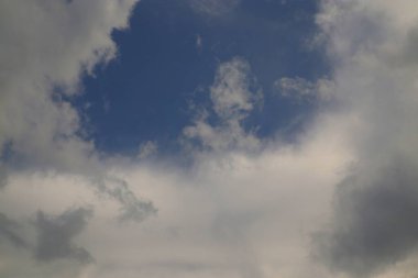 Gökyüzünün çeşitli tipte bulutları gösteren görüntüsü. Mavi gökyüzünü saran beyaz ve gri bulutlar. Bileşim dinamik bir gökyüzü yaratıyor. Işık yumuşak ve dağınık..