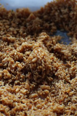 Yakın çekim pişmiş kahverengi pilav. Pirinç, yemeğin bir parçası olarak servis edilmeye hazır görünüyor. Porsiyon bir kase ya da tabakta..