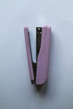 Açık pembe bir zımba beyaz bir arkaplanda duruyor. Pürüzsüz kıvrımları ve pastel rengi işlevsellik ve zarafetin bir karışımı olduğunu gösteriyor. Görüntü bir sakinlik ve düzen hissi veriyor..