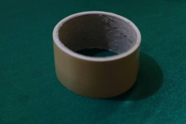 Detaylı bir yakın plan çekimde, zengin bir deniz mavisi zeminine titizlikle yerleştirilmiş bej yapıştırıcılı bir bant rulosu görülüyor. Görüntü dokuya ve ince renk karşıtlıklarına odaklanır.