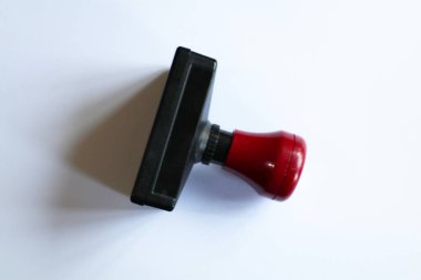 Kauçuk bir damganın izole edilmiş yakın çekimi. Bu araç siyah çerçeve ve kırmızı saptan oluşur. Pul kullanılmamış ve belge veya ofis görevleri için hazır görünüyor.