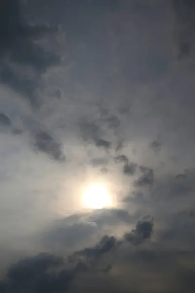 Karanlık ve aydınlık bulutlardan oluşan bir duvar halısıyla kısmen örtülü güneşli bir gökyüzü. Güneş ışınları atmosferik örtüyü delip, dramatik ama sakin bir sahne yaratır..