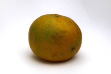 Tek bir portakal beyaz bir arkaplanda oturur, dokusunu ve canlı rengini vurgular..