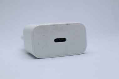 Temiz bir arkaplanda beyaz bir USB C tipi duvar şarj aletinin yakın çekim çekimi. Görüntü, cep telefonları, akıllı telefonlar ve diğer cihazlar için uygun bu şarj cihazının parlak tasarımı ve modern teknolojisini vurguluyor. Ayrı bir yerde.