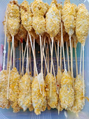 Sempol Ayam 'ın plastik bir konteynırdaki yakın çekimi. Sempol Ayam, baharatlarla tatlandırılmış, ekmek kırıntılarıyla kaplanmış ve sonra da kızartılmış, tapyoka unu ve tavuk etinden yapılan popüler bir Endonezya sokak yiyeceğidir. Bu lezzetli atıştırmalıklar genelde şişte servis edilir. 
